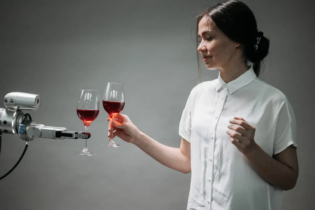A woman and a robotic arm clink glasses of red wine, symbolizing technological harmony.
